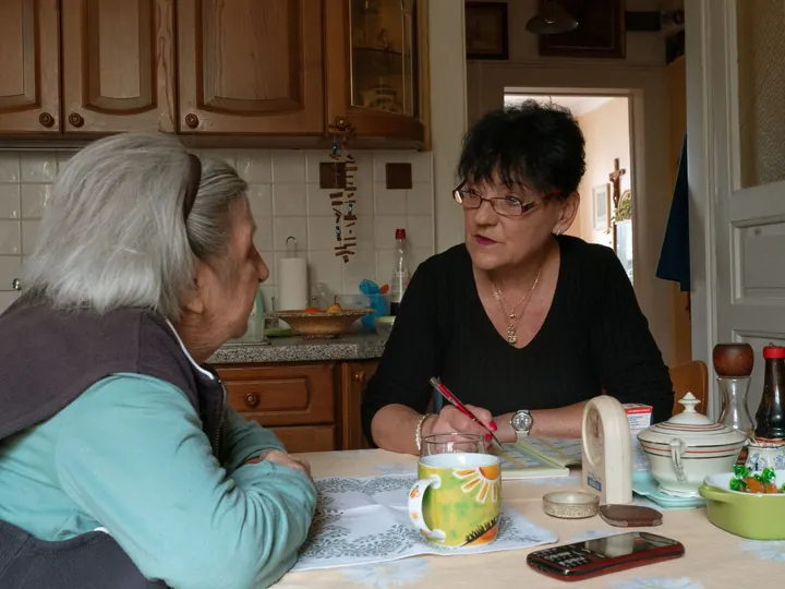 Deux femmes âgées discutent autour d’une table.