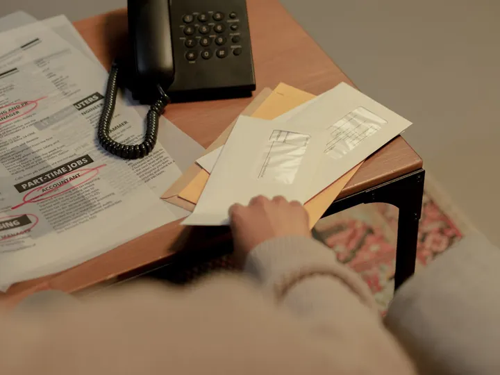 Une personne trie des lettres et des enveloppes sur une table.